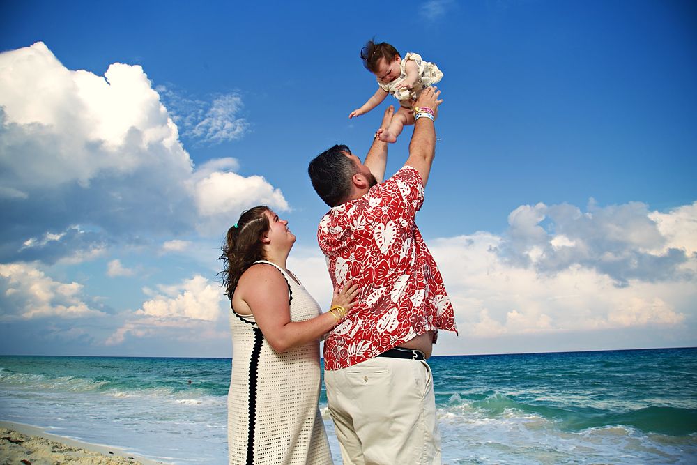 Dad lifting his baby girl into the sky at the beach