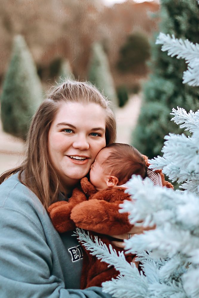 Mom snuggling her baby beside a frosted tree