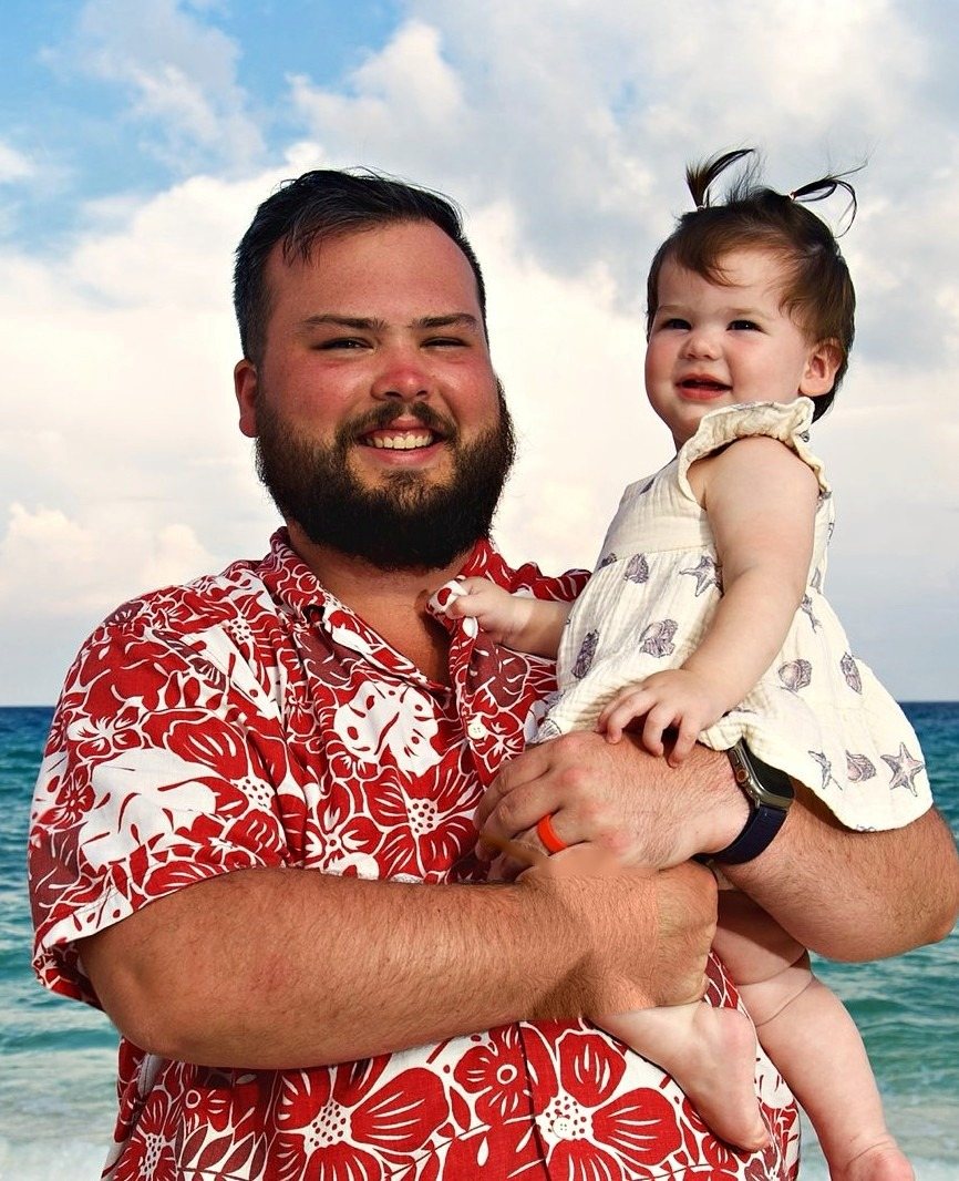 Ethen Harrelson, photographer, holding his daughter on the beach