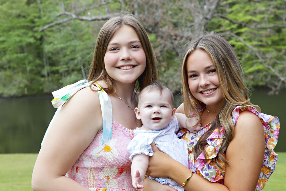 Two sisters holding a baby